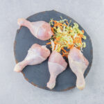Delectable greens and chicken legs on the board, on the white background. High quality photo